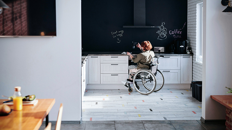 Kvinna i rullstol är i ett kök.